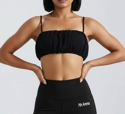 Person wearing a black sports bra / top and leggings with '7th Arena' branding on a light gray background